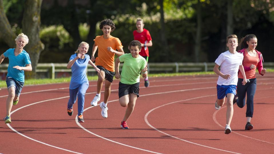 Secondary students running on a track as part of PE summer sports for sports day with athletics, tennis, cricket and rounders