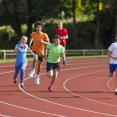 Secondary students running on a track as part of PE summer sports for sports day with athletics, tennis, cricket and rounders