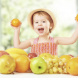 EYFS child holding fruit showing understanding of how bodies, growth and health work