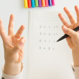 Child Counting On Their Fingers With Addition & Subtraction Sums In The Background