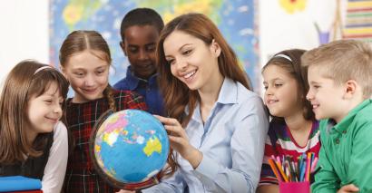 Teachers looking at globe with pupils