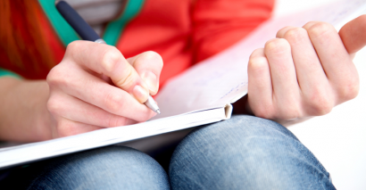 Woman sat with open book and pen marking work