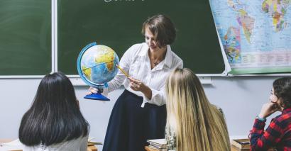 Teacher demonstrating with a globe supporting secondary geography students