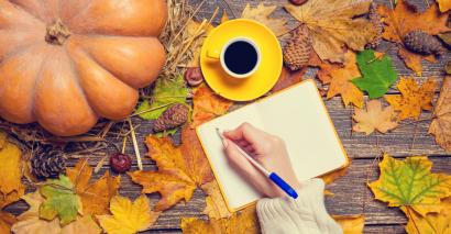Autumn leaves on a table and a person writing autumn poetry to inspire secondary English students