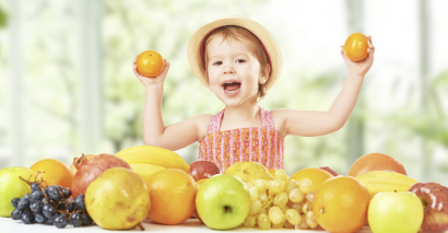 EYFS child holding fruit showing understanding of how bodies, growth and health work