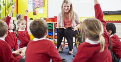 Teacher Surrounded By Engaged Pupils With Reading Activities for Primary