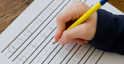 Pupil using a handwriting resource line guide to practice hand writing skills