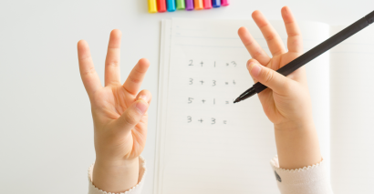 Child Counting On Their Fingers With Addition & Subtraction Sums In The Background