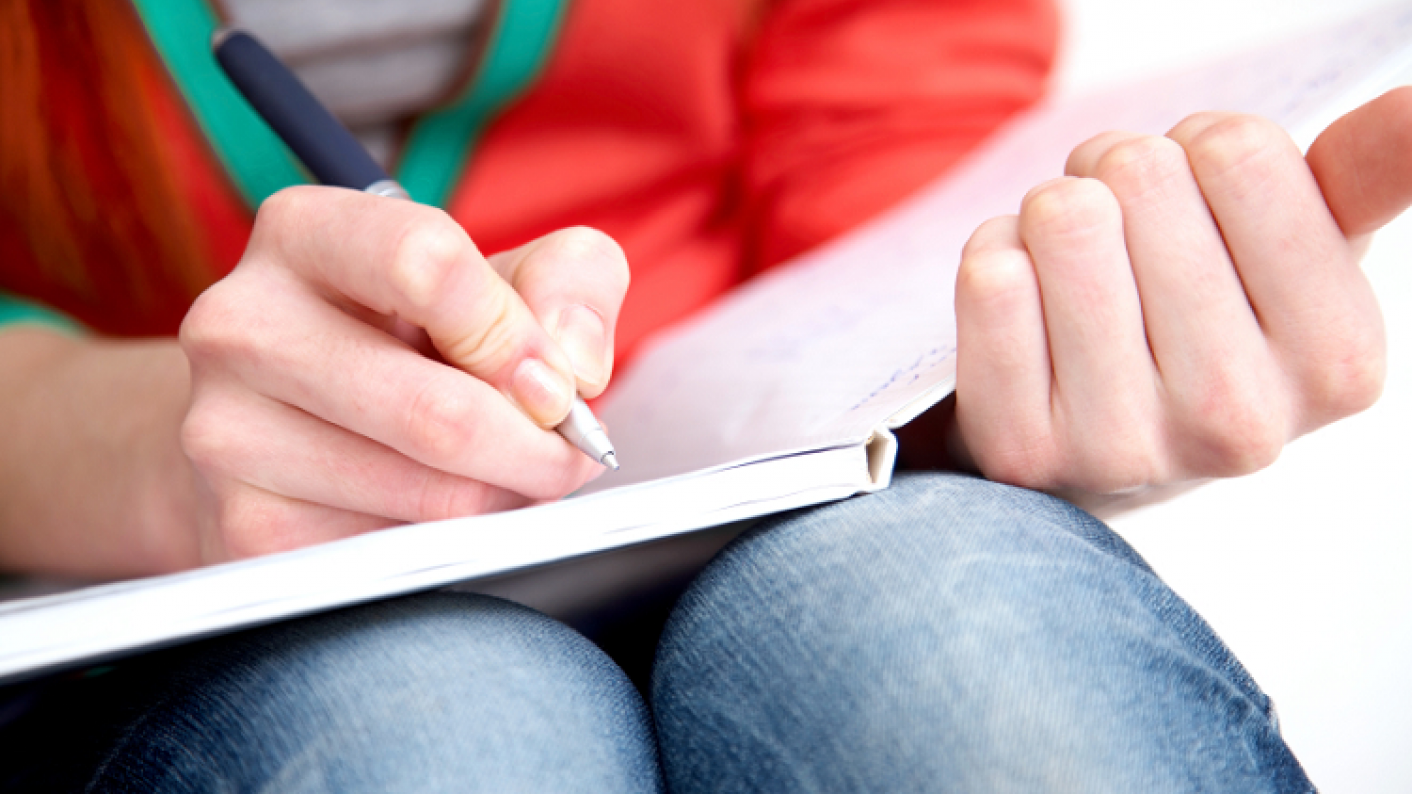 Woman sat with open book and pen marking work