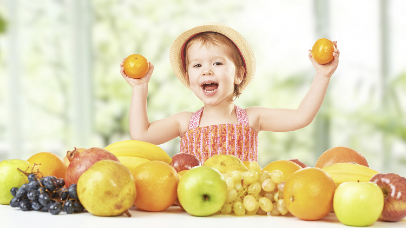 EYFS child holding fruit showing understanding of how bodies, growth and health work