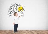 Small boy, surrounded by cartoon question marks and a single lightbulb