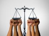 Several multiracial fists prop up the scales of justice