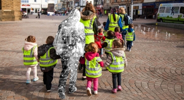 Primary school age children being escorted by an obscured teacher