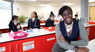 Dame Maggie in a school science lab with students behind her