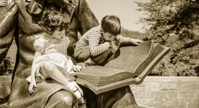 Two children reading a book on a statue