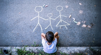 Child looking at chalk drawing of a family
