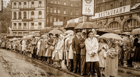 Sepia photograph of people on street under umbrellas