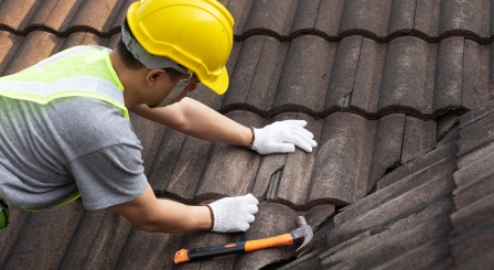 A man wearing a hard hat fixing a roof