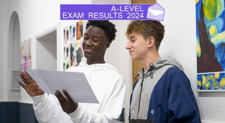 Two teenage boys opening a results envelope