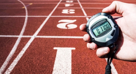 person holding timer showing 11 minutes against backdrop of athletics track