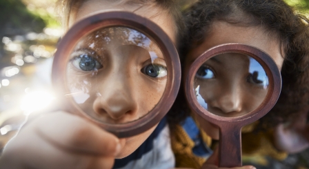 Two children looking through magnifying glasses