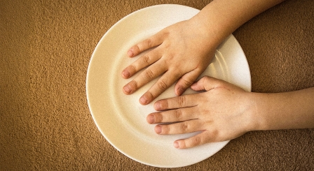 Empty plate with child's hands
