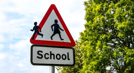 A school road sign with one of the figures running away