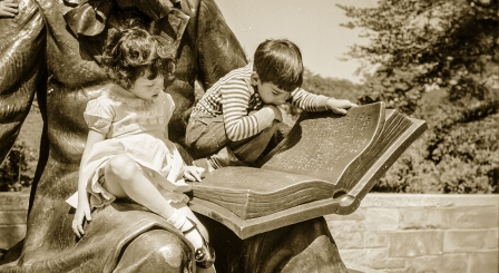 Two children reading a book on a statue