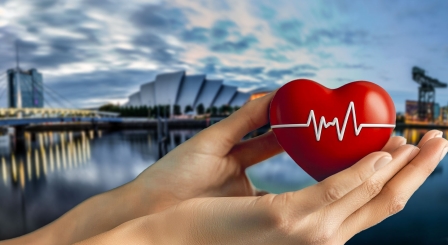 Hands holding heart with backdrop of Glasgow