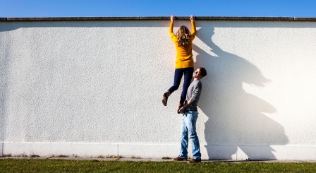 Boy helping a girl over a wall