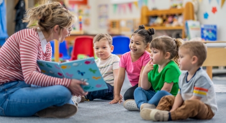 Young children reading with a teacher