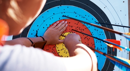 Child pulling arrows out of target board