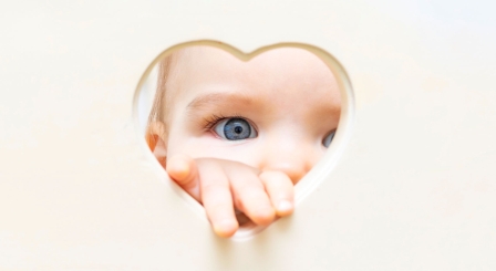 Baby looking through heart shape