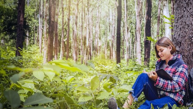 Girl writing in a forest