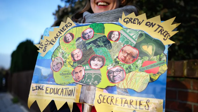 A woman holds her handmade placard as teachers and supporters picket outside Bishop Thomas Grant School, Streatham