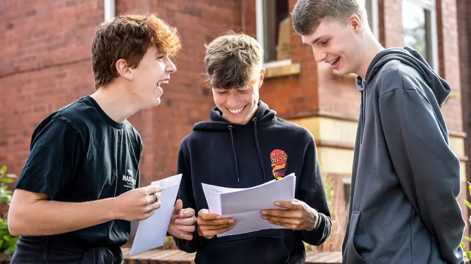 Three students receiving A-level exam results at school