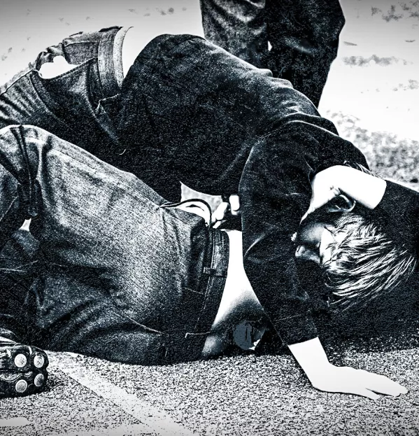 Two boys fighting on pavement