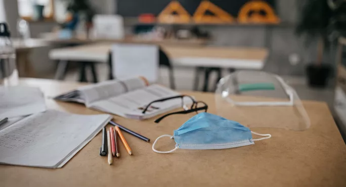 school desk with pens, face mask and science goggles