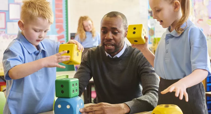 Primary pupils playing with big coloured dice 