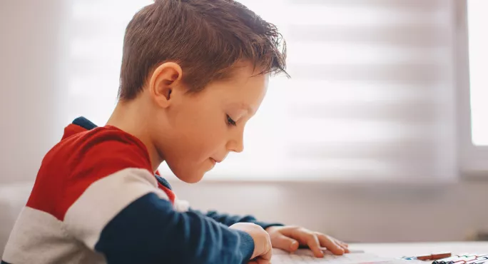 Primary school pupil reading with finger on page 