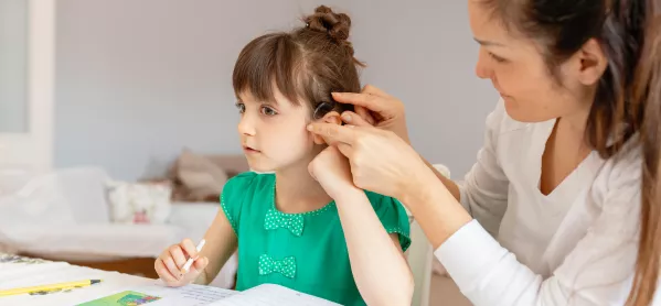 adult helping child with hearing aid