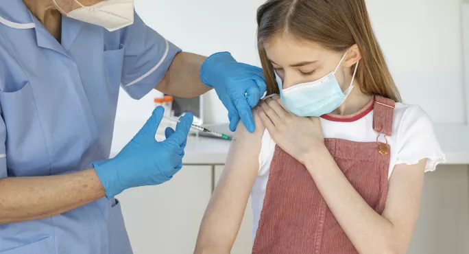 child rolling up sleeve for vaccine