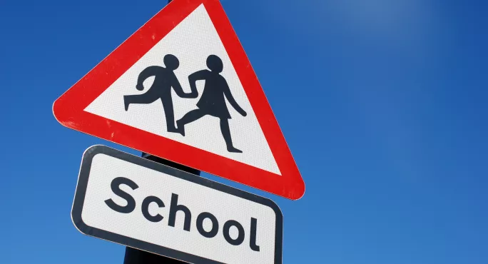 Red triangle road sign with "school"