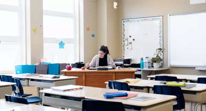 teacher sits in empty classroom