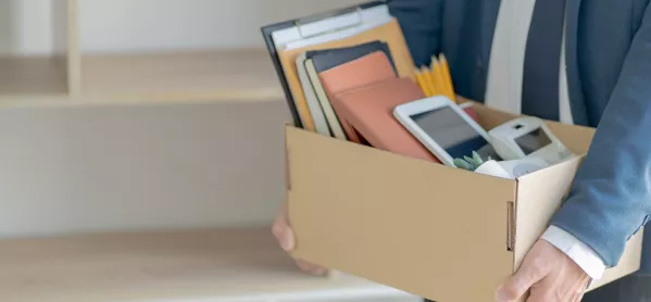 image of person in suit carrying cardboard box of desk possessions 