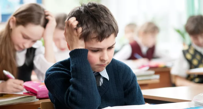 young pupil sits at test holding hair in frustration 