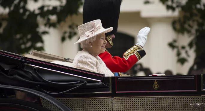 Queen sits in carriage waving 