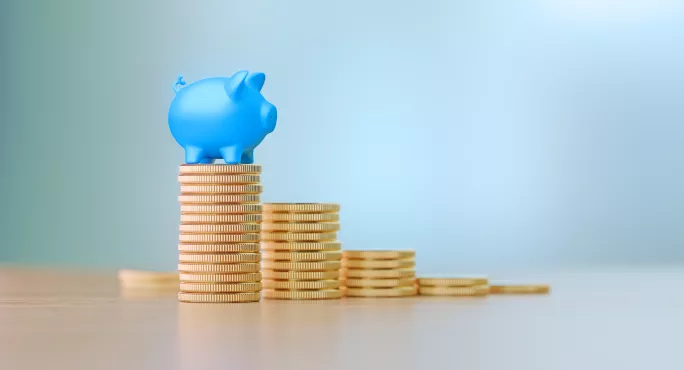 Blue Piggy Bank Sitting On Coin Stacks Before Defocused Background