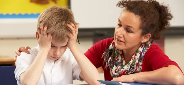 Frustrated school boy working with teacher in the classroom