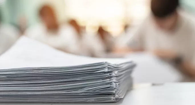 Exam answer sheet or application paper blurry view on table in examination room with blur education background of school university students taking exam test writing answer in seat row with stress